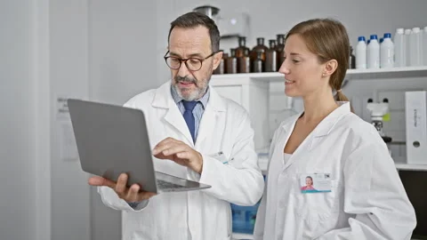 Two dedicated scientists working shoulder-to-shoulder, speaking over lab an.. Stock Footage 268592584