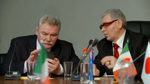 Two delegates show each other something in smartphone during international Stock Footage 76313500