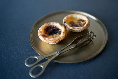 Two delicious Belem cakes (Pasteis de Belem) on a bronze tray, with serving t Stock Photos