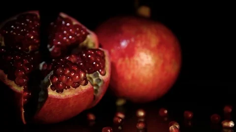 Two delicious, bright, appetizing grenades revolve on a black table. Black Stock Footage 89962806