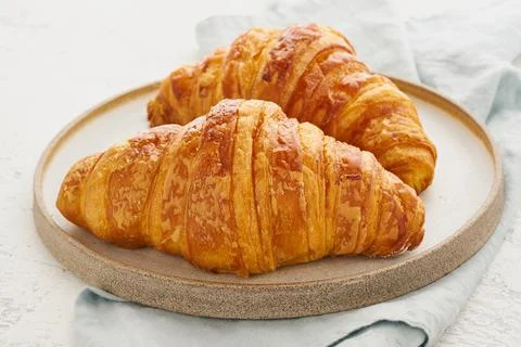 Two delicious croissants on plate and hot drink in mug. Morning French breakfast Stock Photos