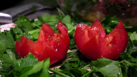 Two delicious tomatoes carved into rosettes lie on green herbs. Stock Footage 341765515