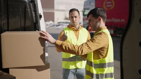 Two delivery men wearing reflective vest searching for a missing parcel in a van Stock Footage 263895478