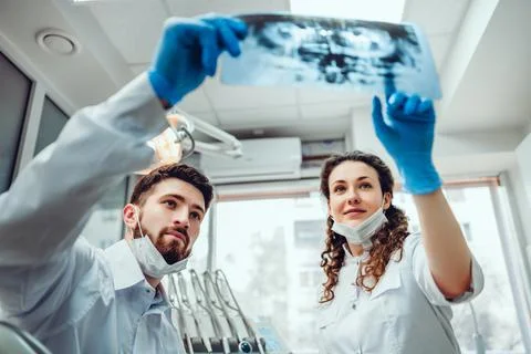 Two dentist doctors looking at X-ray tooth image. Stock Photos
