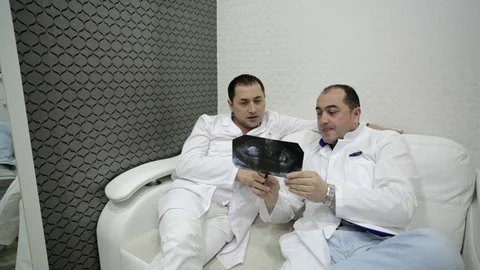 Two dentists have a discussion with x-ray prints Stock Footage 71257758
