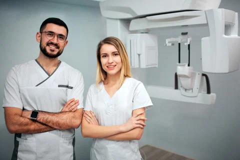 Two dentists stand in x-ray room and pose to camera. They smile and hold hands Stockfoto's