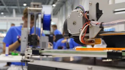 Two designers working in a design studio watch a 3D printer. A man makes a Stock-Footage 81227838