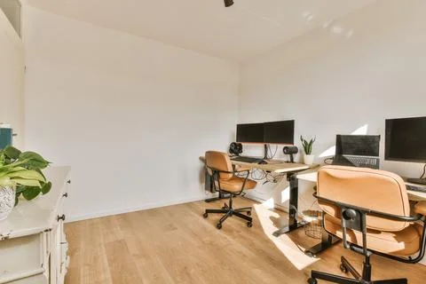 Two desks with two monitors and chairs in a room Stock Photos