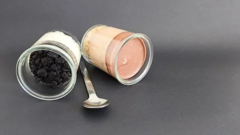 Two dessert jars with a spoon on a dark background Stock Photos