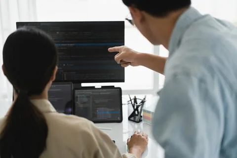 Two developer programmer checking code on multiple monitor while programmin.. 写真素材