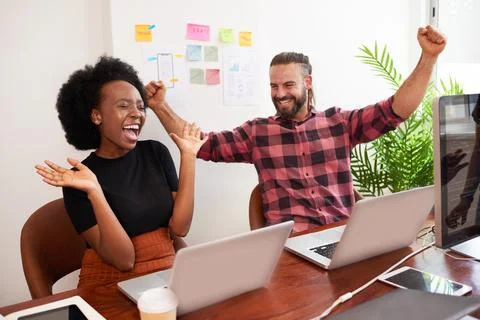 Two developers cheer with arms raised in office, successful launch of product 写真素材