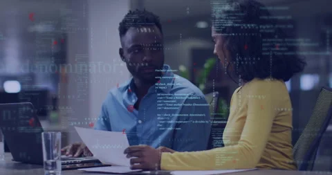 Two developers collaborating over documents and laptop in office, showcasing Stock Footage 308571968