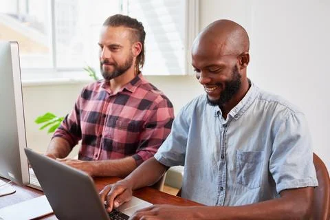 Two developers peer programming together in office, coding side by side 库存照片