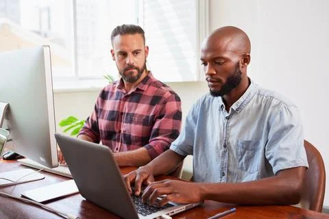 Two developers peer programming together in office, coding side by side Stock-Fotos