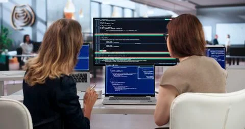 Two Developers Side By Side Discussing Code Changes To Fix Conflicts Quietly. 库存照片
