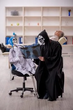 Two devil doctors examining old male patient Foto stock