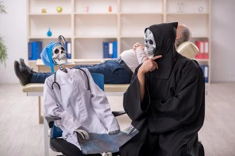 Two devil doctors examining old male patient Stock Photos