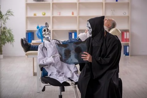 Two devil doctors examining old male patient 스톡 사진