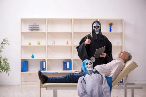 Two devil doctors examining old male patient Stock Photos