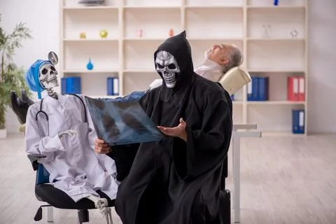 Two devil doctors examining old male patient Foto stock
