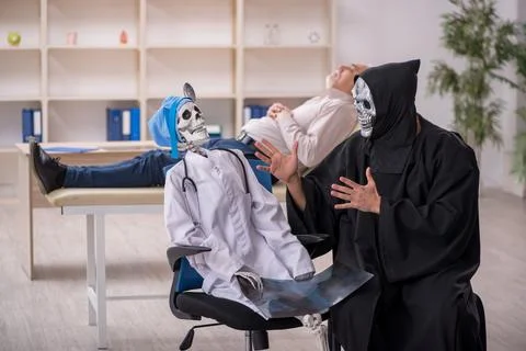 Two devil doctors examining old male patient Foto stock