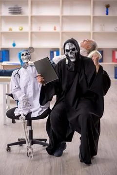 Two devil doctors examining old male patient 库存照片