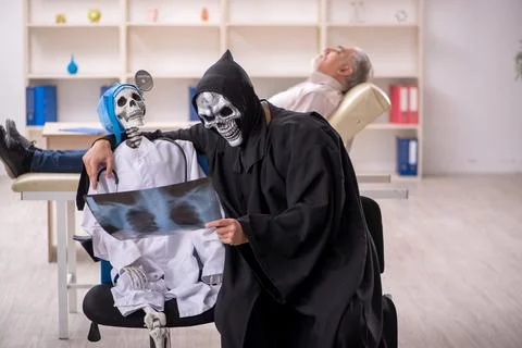 Two devil doctors examining old male patient Foto stock