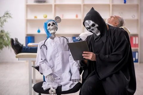 Two devil doctors examining old male patient 스톡 사진