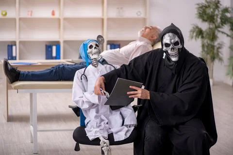 Two devil doctors examining old male patient Stockfoto's