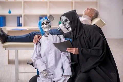 Two devil doctors examining old male patient Foto stock