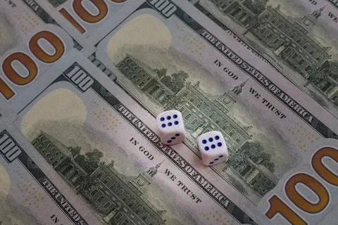 Two dice with sixes up lie on spread out hundred-dollar bills, big win, gambl Stock Photos