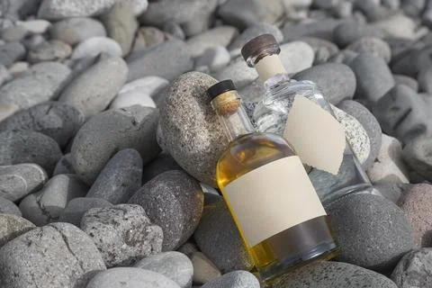 Two different bottles filled with a drink lie on the stones Stock Photos