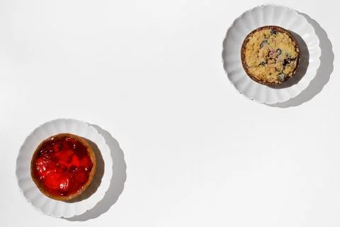 Two different cheesecakes with wild berries on a white table. Stock Photos
