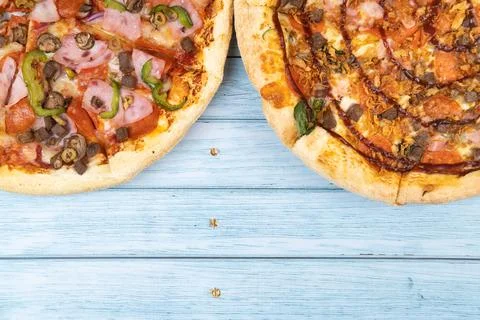 Two different delicious big pizzas on a blue wooden background Stock Photos