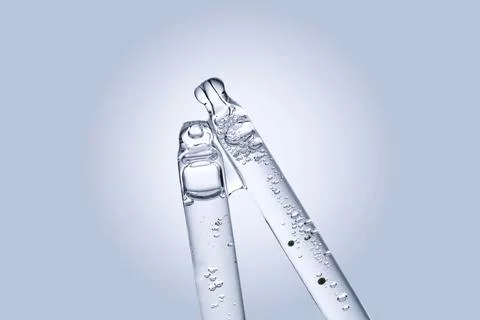 Two different face serum pipettes on a neutral background. Stock Photos