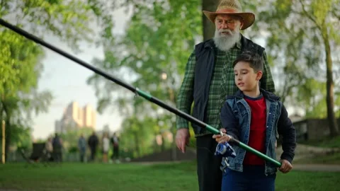 Two different generations catching fish together outside. Grandchild enjoying Stock Footage 260369436