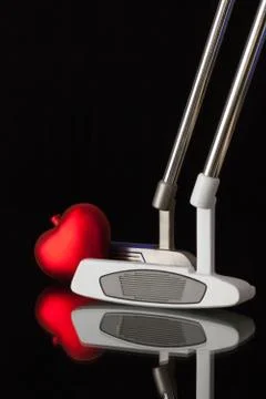 Two different golf putters and red heart 库存照片