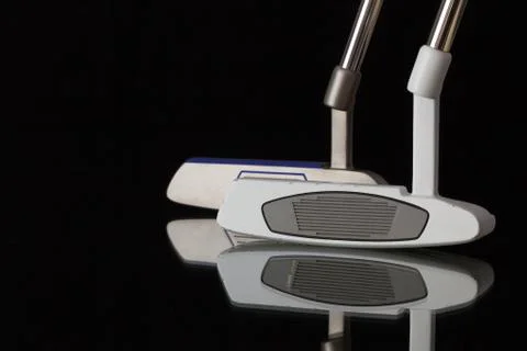 Two different golf putters on a black glass  table Stock Photos