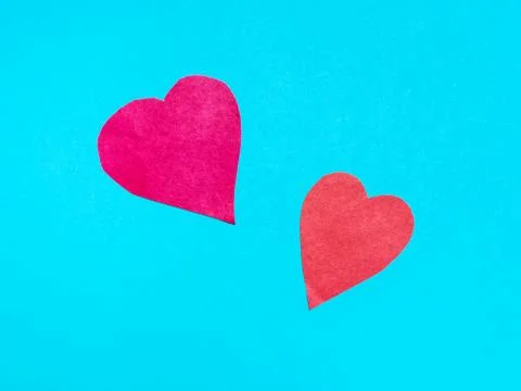 Two different hearts cut from red papers on blue Stock Photos