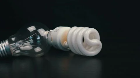 Two different light bulbs on black table Stock Footage 105745310