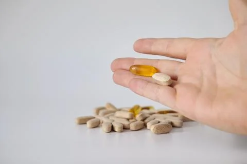 Two Different Pills Held Above a Pile of Tablets Stock Photos