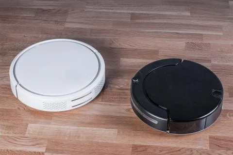 Two different Robotic vacuum cleaners, efficient dust absorption in absence o Stock Photos