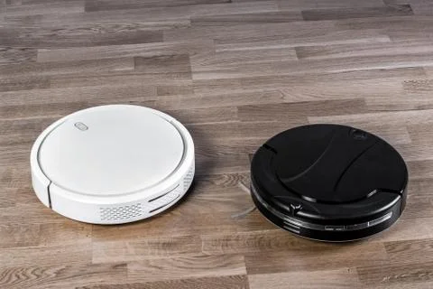 Two different Robotic vacuum cleaners on laminate floor, smart home robotics  Stock Photos