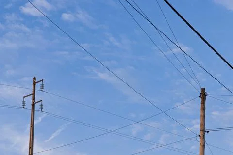 Two different types of utility poles, one modern and one older, stand against Stock Photos