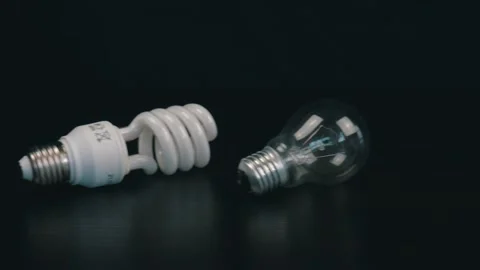 Two diffrent light bulbs on black table. Camera moves from right to left Stock Footage 105745258