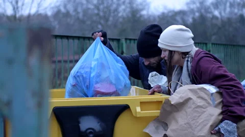 Two dirty and poorly dressed homeless people, a man and a woman, are looking for Stock Footage 226380792