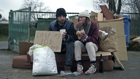 Two dirty and poorly dressed homeless people, a man and a woman, are sitting Stock Footage 239143344