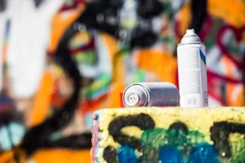 Two Discarded Spray Cans in Front of Graffiti Wall Stock Photos