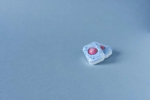 Two dishwasher capsules on blue background, free space for text. Stock Photos