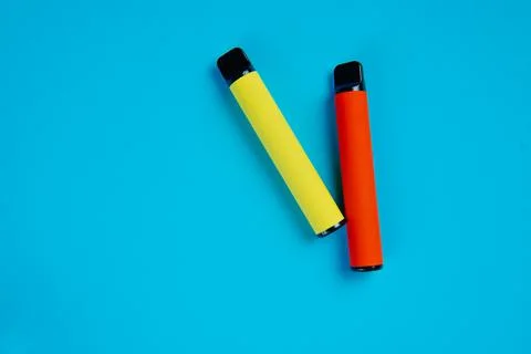 Two disposable e-cigarettes on a blue background. Electronic vape, an alterna Stock Photos